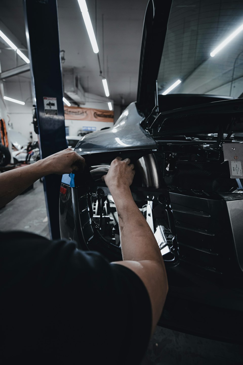 Mani di meccanico che lavorano sul pannello posteriore di un'auto.